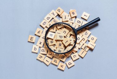 Kare ahşap karolardan yapılmış İngiliz alfabesi mavi arkaplana saçılmış. Düşünce geliştirme konsepti, dil bilgisi.