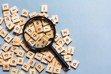 Kare ahşap karolardan yapılmış İngiliz alfabesi mavi arkaplana saçılmış. Düşünce geliştirme konsepti, dil bilgisi.