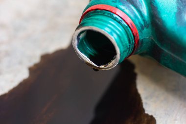 Eski motor yağı şişesi, eski siyah yağ yağı kayganlaştırıcısı, kullanılmış araba motoru beton zemine dökülmüş..