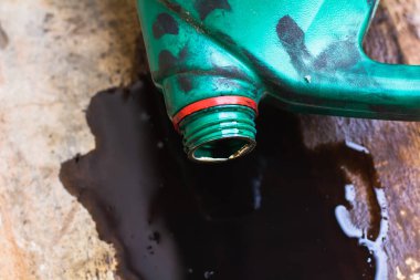 Eski motor yağı şişesi, eski siyah yağ yağı kayganlaştırıcısı, kullanılmış araba motoru beton zemine dökülmüş..