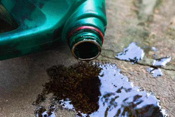 Eski motor yağı şişesi, eski siyah yağ yağı kayganlaştırıcısı, kullanılmış araba motoru beton zemine dökülmüş..