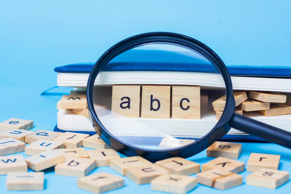 English alphabet made of square wooden tiles with the English alphabet scattered on blue background. The concept of thinking development, grammar.