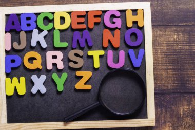 Kare ahşap karolardan yapılmış İngilizce harfler siyah arkaplana dağılmış İngilizce harfler var. Gramer düşüncesi geliştirme kavramları