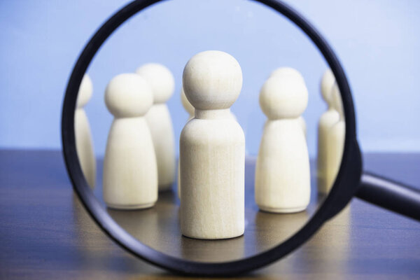 Концептуальный поиск бизнес-лидерства, бизнесмена, квалифицированного персонала, ручного держания увеличительного стекла, акцент на деревянной кукле