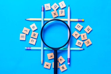 Mavi arkaplana yerleştirilmiş kalem ve İngilizce harfler, İngilizce öğrenme kavramı