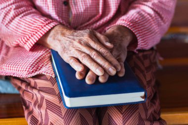 Bir sandalyede oturan yaşlı bir kadının evinde kitap okurkenki yakın çekimi. Emeklilikten sonraki yaşam konsepti