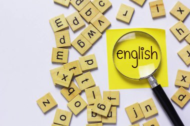 İngilizce öğrenme kavramını temsil eden açık pembe arkaplan üzerine dağılmış İngilizce harfler.