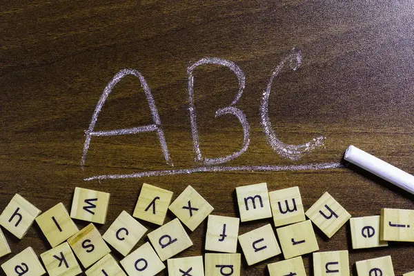 Tahta masa yüzeyine dağılmış İngiliz harfleri. Dil bilgisi düşünme becerileri ve İngilizce öğrenme fikri.