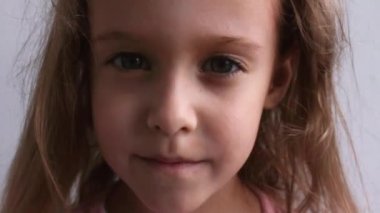 Gülen çocuksu bebek portresi. Güzel küçük bir kız kameraya gülümsüyor. Video.