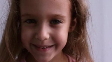 Gülen çocuksu bebek portresi. Güzel küçük bir kız kameraya gülümsüyor. Video.