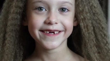 Şirin küçük kız gülümsüyor ve ön süt dişlerini gösteriyor. Diş büyümesi. Yakın plan. 6 yaşındaki bir Rebec 'in portresi.