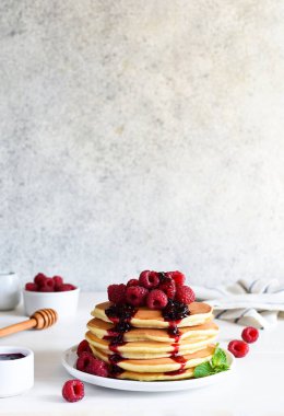 Beyaz arka planda kahvaltıda ahududu ve reçelli ev yapımı krepler.