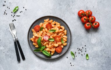 Beton zemin üzerinde domates soslu makarna ve kiraz domatesleri, üst manzara, metin için boşluk.