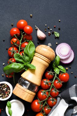 Biber öğütücü, fesleğen, baharat ve sebzeler siyah mutfak masasında yazılı. Yiyecek malzemeleri..