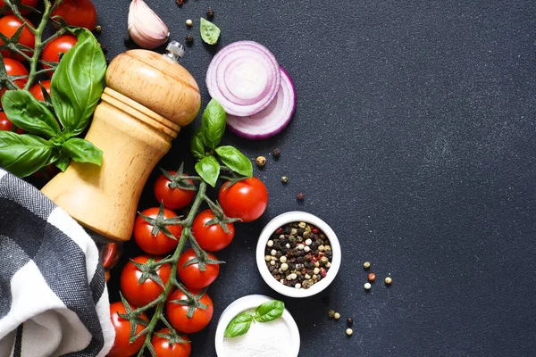 stock image Pepper grinder, basil, spices and vegetables on a kitchen black table with space for text. Food ingredients.