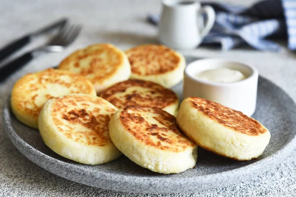 stock image Homemade cheesecakes in a concrete plate and sour cream. Word sauce and cottage cheese casserole.