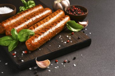 Koyu arkaplanda ahşap bir tahtada baharatlı ızgara sosis.