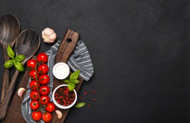 Spatula, mutfak havlusu ve siyah arka planda domatesler. Gıda arkaplanı
