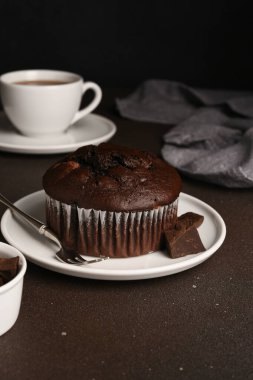 Koyu arkaplanda çikolatalı kek ve bir fincan çay. Brownie cupcake.