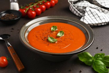 Koyu arkaplanda fesleğenli taze domates çorbası.