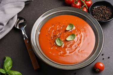 Koyu arkaplanda fesleğenli taze domates çorbası.