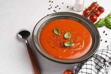 Beyaz arka planda fesleğenli taze domates çorbası.