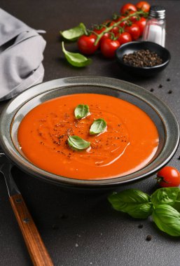 Koyu arkaplanda fesleğenli taze domates çorbası.