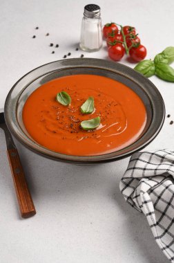 Beyaz arka planda fesleğenli taze domates çorbası.