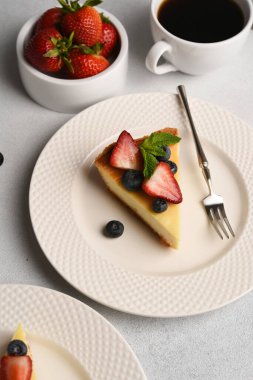 New York peynirli kek dilimi, böğürtlenli ve bir fincan kahveli.