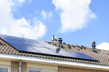 Evin çatısındaki güneş pili, açık bulutlu mavi gökyüzünün arka planına karşı. Alternatif enerji kaynakları.