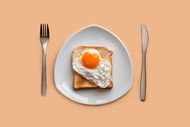 Ekmek kızartma makinesinde çırpılmış yumurta. Pembe arka planda, beyaz bir tabakta, üst tarafta..