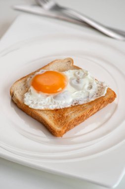 Çırpılmış yumurta tost makinesinde kızarmış ekmek dört köşeli beyaz tabakta beyaz masa, üst manzara..