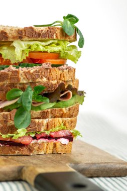  Çeşitli dolgularla dolu birkaç sandviç beyaz masadaki tahtanın üzerinde duruyor.