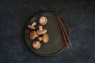 Şii 'lerin bir grup mantarı siyah bir seramik tabakta uzanıyor. 