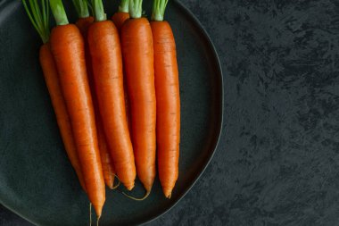 Siyah seramik tabakta yeni bir havuç hasadı.