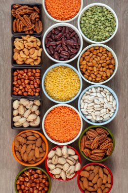 Çok renkli seramik kaselerde, ahşap bir masadaki çok renkli seramik kaselerde çeşitli fındık, fasulye ve mercimek çeşitleri. Sağlıklı beslenme ve sağlıklı yaşam kavramı, 