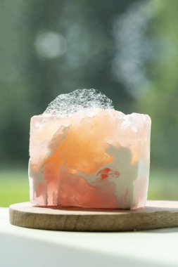 Bar parlak renkler ve köpük dokusu ile el yapımıydı beyaz bir masa üzerinde ahşap bir tezgah üzerinde yeşil doğa karşı