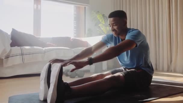 若いアフリカ系アメリカ人の黒人男性は 彼のリビングルームで運動マットに取り組む前に足を伸ばし 自宅で洞窟 自宅で運動 4Kビデオ — ストック動画