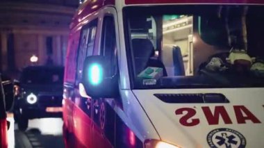 Eski bir Avrupa şehrinde gece vakti park halindeki bir ambulansın el fenerleriyle yakın çekim görüntüsü. Gece ambulansla. Ambulansta gece vardiyası. Çalışan el fenerli ambulans arabası. Yüksek kalite 4k görüntü
