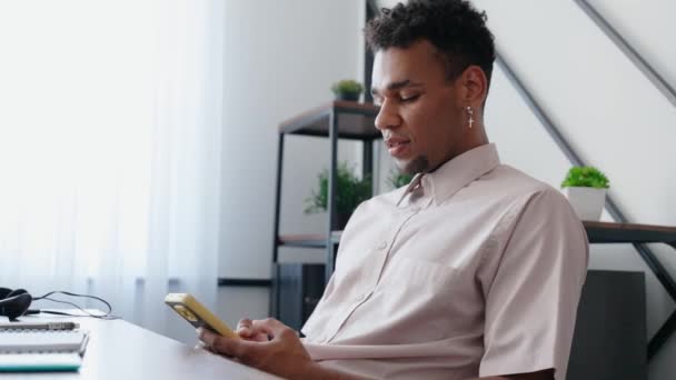 Hombre Negro Usa Teléfono Mientras Está Sentado Escritorio Oficina Colegas — Vídeo de stock