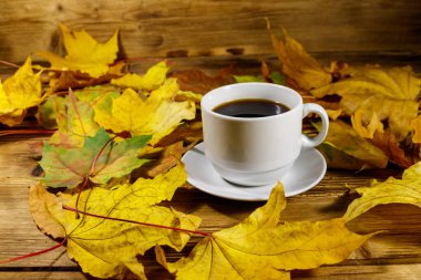 Bir fincan kahve ve sonbahar akçaağaç yaprakları ahşap masada. Sonbahar konsepti