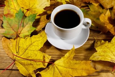Bir fincan kahve ve sonbahar akçaağaç yaprakları ahşap masada. Sonbahar konsepti