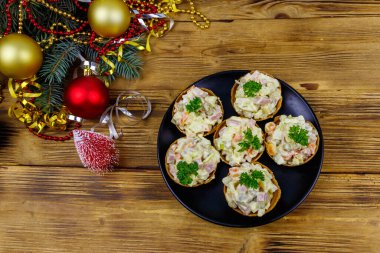 Geleneksel Rus şenlik salatası Olivier tartlarda ve Noel süslemeleri ahşap masada. Üst görünüm
