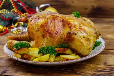 Tavuğun tamamını patates ve Noel süslemeleri ile ahşap bir masada pişirdim.