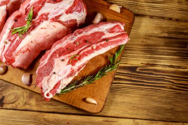 Ahşap masada baharat, sarımsak ve biberiye ile çiğ domuz kaburga. Üstte görüntü
