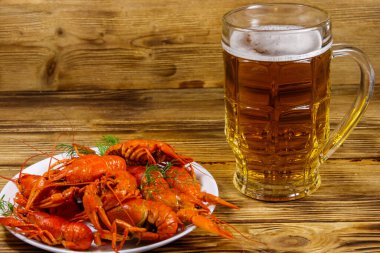 Haşlanmış kerevit ve bir kupa bira ahşap masada.