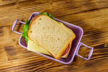 Tahta bir masanın üzerinde sandviçlerle beslenme çantası. Üst görünüm