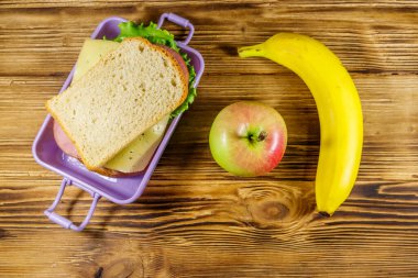 Sandviç, muz ve elmayla dolu bir beslenme çantası. Üst görünüm