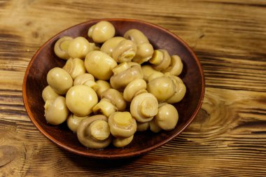 Seramik tabak turşusu petrol ile. Ahşap masa üzerinde Marine mantar