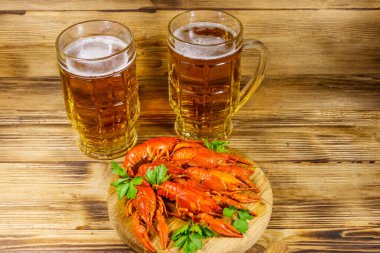 Haşlanmış kerevit ve tahta bir masada iki kupa bira.